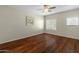 Cozy bedroom featuring wood floors, a ceiling fan, and windows for natural light at 16219 W Woodlands Ave, Goodyear, AZ 85338