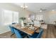 Open concept dining room with a wood table, blue chairs, and views into the living room at 16219 W Woodlands Ave, Goodyear, AZ 85338