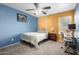 Bright bedroom with blue and yellow walls, ceiling fan, desk and chair, and comfortable bed at 16528 W Pierce St, Goodyear, AZ 85338