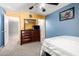 Well-lit bedroom with large dresser, blue accent wall, ceiling fan, and framed art at 16528 W Pierce St, Goodyear, AZ 85338