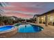 Beautiful backyard with a shimmering pool, hot tub, lounge chairs, and outdoor seating area at sunset at 17793 W Corrine Dr, Surprise, AZ 85388