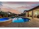 Beautiful backyard with a shimmering pool, hot tub, lounge chairs, and outdoor seating area at sunset at 17793 W Corrine Dr, Surprise, AZ 85388