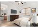 Bedroom features carpet flooring, ceiling fan, window, television, and access to an ensuite bathroom at 23116 N Padaro Ct, Sun City West, AZ 85375