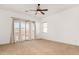 Large primary bedroom offering sliding glass doors to a patio, a ceiling fan, and neutral carpeting at 23116 N Padaro Ct, Sun City West, AZ 85375