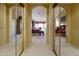 Hallway with mirrored closet doors leads to primary bedroom suite with sitting area and ensuite bath at 23731 S Angora Dr, Sun Lakes, AZ 85248