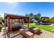 Outdoor kitchen with built-in grill and bar seating, alongside a cozy fire pit and lush lawn by the pool at 2422 W Aloe Vera Dr, Phoenix, AZ 85085