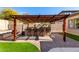 Stylish outdoor kitchen with pergola, bar seating, and lush green space, perfect for entertaining at 2422 W Aloe Vera Dr, Phoenix, AZ 85085