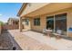 A covered patio with brick pavers, perfect for relaxation, with a small table and easy access to the home's interior at 24670 N 171St Ln, Surprise, AZ 85387