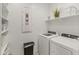 A bright laundry room featuring a modern washer and dryer, ample shelving, and organized storage solutions at 24670 N 171St Ln, Surprise, AZ 85387