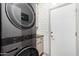 This laundry room features a gray stackable washer and dryer, white subway tile and gray cabinets at 2528 E La Costa Dr, Chandler, AZ 85249