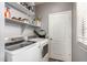 Well-organized laundry room with white shelves, washer, dryer, and convenient storage for supplies at 2645 W Florentine Rd, Phoenix, AZ 85086