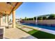 Backyard pool with water feature, outdoor kitchen area, and landscaping with grassy pavers at 2799 E Waterman St, Gilbert, AZ 85297