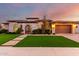 Elegant stone home featuring an arched entry gate, manicured lawn, and attached two car garage at 2799 E Waterman St, Gilbert, AZ 85297