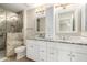 Modern bathroom with double sink vanity, decorative mirrors, and large stone tiled walk-in shower with glass doors at 4040 E Rowel Rd, Phoenix, AZ 85050