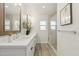 Bright bathroom featuring a double sink vanity with quartz countertops, wood-look floors, and a glass-enclosed shower at 5412 E Tierra Buena Ln, Scottsdale, AZ 85254