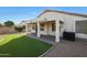 Backyard featuring a covered patio, artificial grass, and desert landscaping at 6516 W Matilda Ln, Glendale, AZ 85308