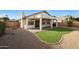 Backyard featuring a covered patio, artificial grass, and desert landscaping at 6516 W Matilda Ln, Glendale, AZ 85308