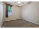 The simple bedroom has neutral carpeting, paint, a ceiling fan, and a window at 6516 W Matilda Ln, Glendale, AZ 85308