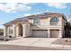 Two-story home with arched entryway, beige stucco exterior, spacious three-car garage and desert landscaping at 7318 W Paso Trl, Peoria, AZ 85383