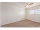 Cozy bedroom with neutral carpet, bright window and a ceiling fan providing comfort and natural light at 7539 N 50Th Ave, Glendale, AZ 85301