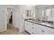 Bright bathroom featuring double sinks, white cabinetry, modern fixtures, and closet access at 7924 S 24Th Pl, Phoenix, AZ 85042