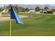 Lush green golf course with blue flag on a sunny day, mountains in the background at 8233 E Calypso Ave, Mesa, AZ 85208