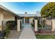 Welcoming front entrance features a walkway and a charming brick wall, complete with lush landscaping and a vibrant tree at 10808 W Kelso Dr, Sun City, AZ 85351