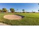 Scenic golf course with a sand trap, lush green fairways, and mature trees in the background at 10808 W Kelso Dr, Sun City, AZ 85351