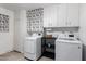 Well-lit laundry room features updated appliances, white cabinetry, and a charming decorative window covering at 10808 W Kelso Dr, Sun City, AZ 85351