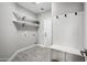 Bright laundry room with open shelving, white cabinets, and wood-look tile flooring at 11537 W Laurelwood Ln, Avondale, AZ 85392