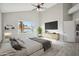 Bright main bedroom featuring a comfortable bed, TV console, a palm tree, and grey floors at 11537 W Laurelwood Ln, Avondale, AZ 85392