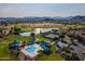 Aerial view of a community pool, playground, and lake surrounded by lush green spaces and desert mountains at 30263 N Bobcat Way, San Tan Valley, AZ 85143