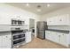 Bright kitchen featuring white cabinets, stainless steel appliances, tile flooring and access to the laundry room at 30263 N Bobcat Way, San Tan Valley, AZ 85143