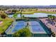 Aerial view of well-maintained tennis courts next to a scenic lake and golf course in a residential community at 30263 N Bobcat Way, San Tan Valley, AZ 85143