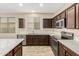 Modern kitchen features dark wood cabinets, stainless appliances, white countertops, and hardwood floors at 39559 N Prairie Ln, Anthem, AZ 85086