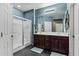 A full bathroom featuring double sinks, dark cabinets, and a glass-enclosed shower with blue-green walls at 42072 W Dorsey Dr, Maricopa, AZ 85138