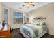 A bright bedroom featuring a large window, a ceiling fan, and a comfortable looking bed at 42072 W Dorsey Dr, Maricopa, AZ 85138