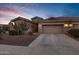 Charming single-Gathering home featuring a desert landscape, tile roof, and a two-car garage against a blue sunset sky at 42072 W Dorsey Dr, Maricopa, AZ 85138