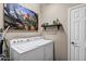 A clean and bright laundry room with a large painting on the wall, a washer and dryer at 42072 W Dorsey Dr, Maricopa, AZ 85138