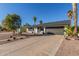 Single-story home featuring a two-car garage, desert landscaping, and mature palm trees on a sunny day at 520 E Jahns Pl, Casa Grande, AZ 85122