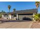 Single-story home featuring a two-car garage, desert landscaping, and mature palm trees on a sunny day at 520 E Jahns Pl, Casa Grande, AZ 85122