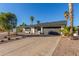 Single-story home featuring a two-car garage, desert landscaping, and mature palm trees on a sunny day at 520 E Jahns Pl, Casa Grande, AZ 85122