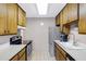 Galley kitchen featuring stainless steel appliances, white counters, and wood cabinets; next to dining area at 5525 E Thomas Rd # O8, Phoenix, AZ 85018