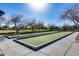 Bocce ball court, framed by mature trees, offers a leisurely activity within a well-maintained community setting at 5652 W Cinder Brook Way, Florence, AZ 85132