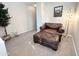 Inviting sitting area with leather chair, ottoman, decorative tree, and neutral carpeted floors at 1042 S Cheshire Ln, Gilbert, AZ 85296