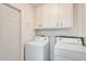 Laundry room features white appliances, upper cabinets for storage, and convenient access to the doorway at 10891 W Clair Dr, Sun City, AZ 85351