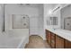 Bright bathroom featuring a soaking tub, a glass shower and a dual sink vanity at 11910 W Daley Ct, Sun City, AZ 85373