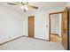 Neutral bedroom featuring a ceiling fan and neutral carpet flooring, with a wood door and trim at 1201 W Dahlia Dr, Phoenix, AZ 85029