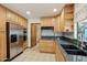 Kitchen featuring stainless appliances, wood cabinets, dark countertops, and tile backsplash and flooring at 1201 W Dahlia Dr, Phoenix, AZ 85029