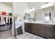 Bathroom featuring a double sink vanity with dark cabinets, a large mirror, and a walk-in closet at 12716 W Mclellan Rd, Glendale, AZ 85307